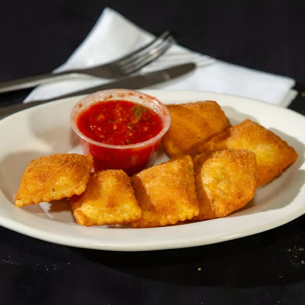 Golden fried ravioli with a side of red marinara sauce on a white plate at Monjunis.