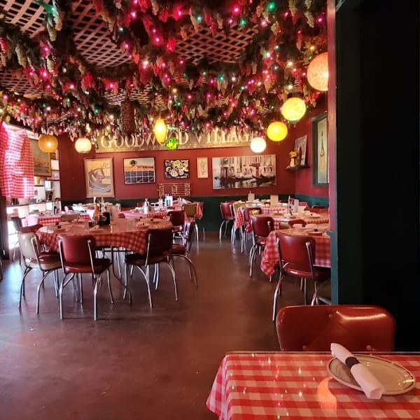 Monjunis Italian Cafe dining room with red and white checkered tablecloths, red chairs, and festive ceiling lights.